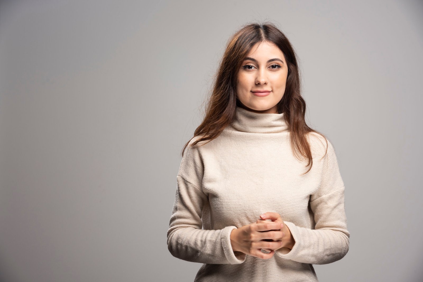 Portrait of a young woman posing on a gray wall . High quality photo